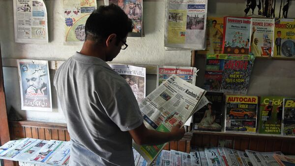 Мужчина читает газету в киоске в Сринагаре