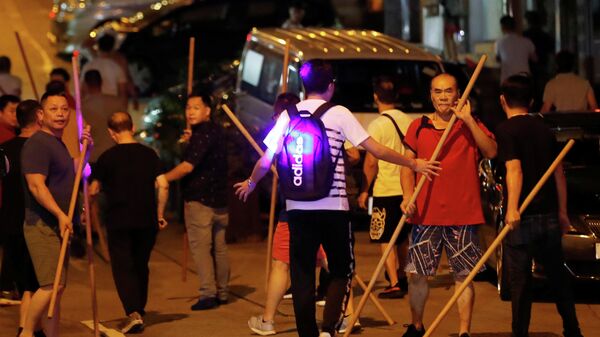 Группа людей с прутами, пытается напасть на антиправительственную демонстрацию в Гонконге. 5 августа 2019