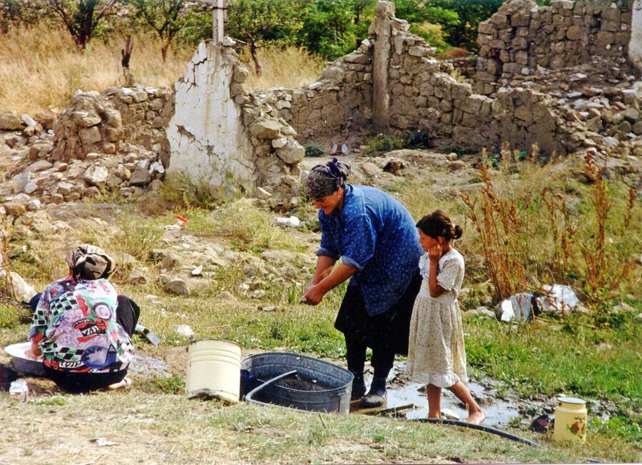 Женщина стирает вещи у разрушенного села в Ботлихском районе Дагестана 