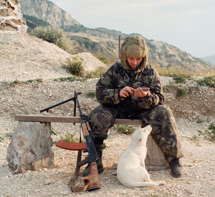Исламский боевик разрубает еду для собаки на позиции в Ботлихском районе Дагестана 