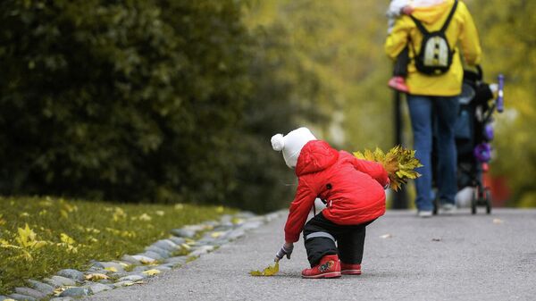 Ребенок собирает осенние листья в парке
