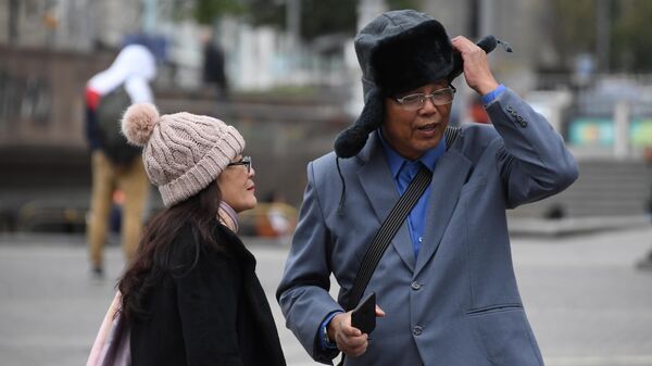 Иностранные туристы одевают теплые головные уборы на Манежной площади