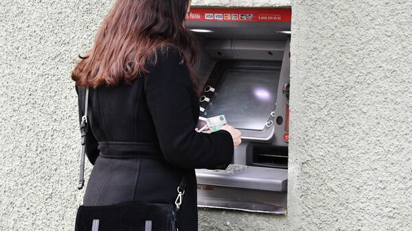 Женщина снимает наличные в банкомате