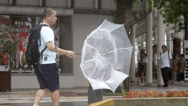 Мужчина во время дождя, вызванным тайфуном Кроса в Миядзаки