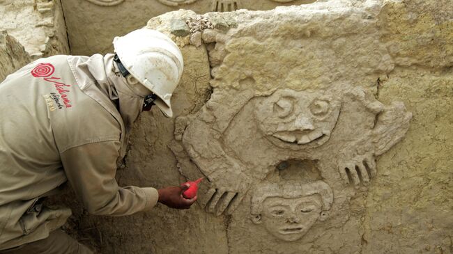 Специалист обрабатывает стену с избражением жабы  на археологических раскопках Вичама в районе Вегета, провинция Уаура, Перу