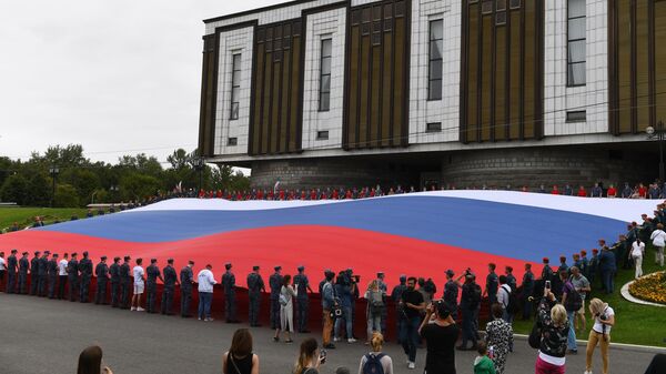 Участники флешмоба развернули государственный флаг Российской Федерации на площади Парка Победы на Поклонной горе в рамках празднования Дня государственного флага России