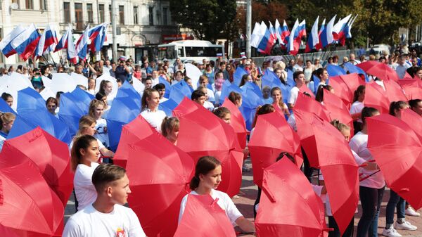 Участники мероприятий составили из зонтов российский триколор в рамках празднования Дня государственного флага Российской Федерации в центре Симферополя
