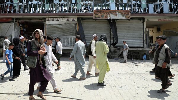 Люди проходят мимо здания с выбитыми окнами на месте взрыва в Кабуле, Афганистан