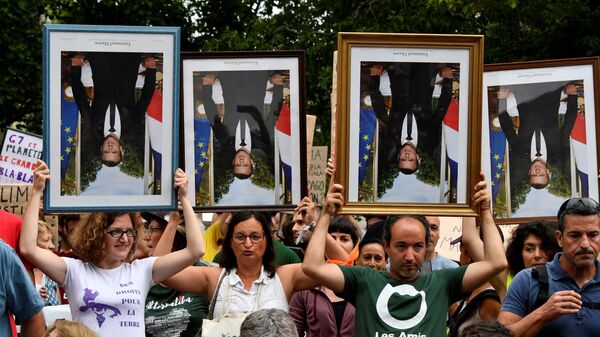 Протестующие держат перевернутые портреты президента Франции Эммануэля Макрона во время акции в городе Байонна, юго-западная Франция. 25 августа 2019 