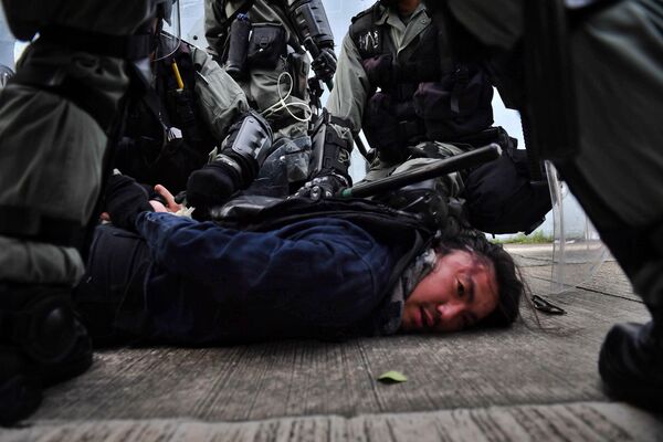 Сотрудники полиции задерживают протестующего в Коулуне, Гонконг