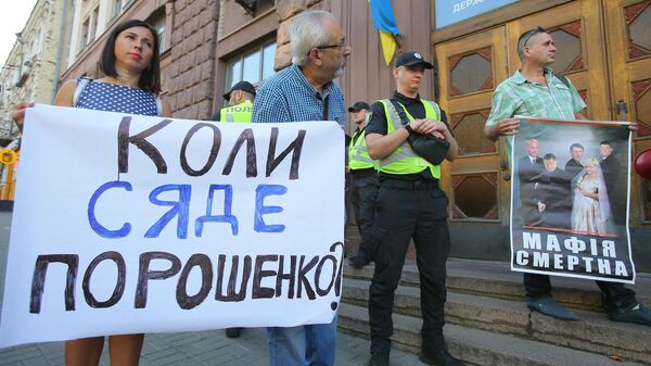 Участники акции против экс-президента Украины Петра Порошенко стоят с плакатами у здания Государственного бюро расследований