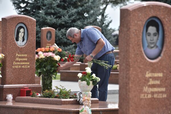 Мужчина принес цветы на могилу на мемориальном кладбище Город ангелов в Беслане, где похоронены погибшие во время теракта в 1-й Бесланской школе 1-3 сентября 2004 года