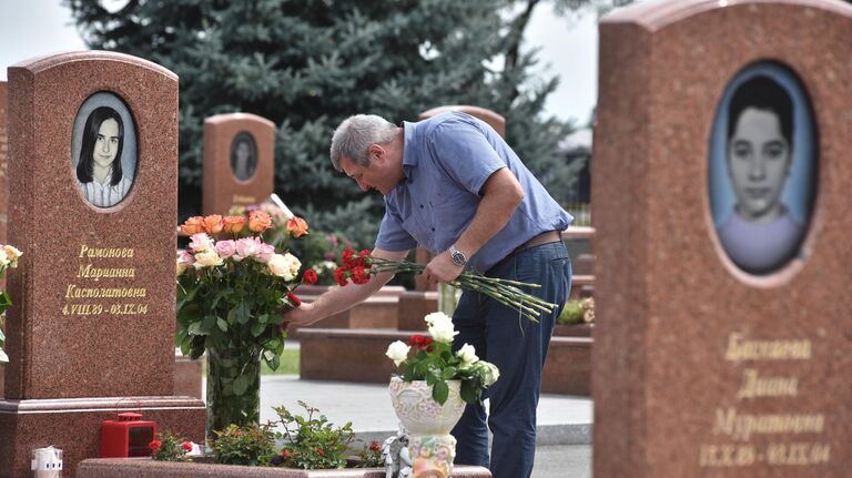 Мужчина принес цветы на могилу на мемориальном кладбище Город ангелов в Беслане, где похоронены погибшие во время теракта в 1-й Бесланской школе 1-3 сентября 2004 года