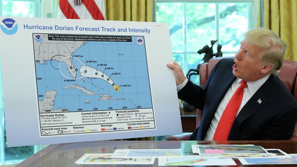 Президент США Дональд Трамп держит диаграмму, показывающую первоначальный прогнозируемый след урагана Дориан