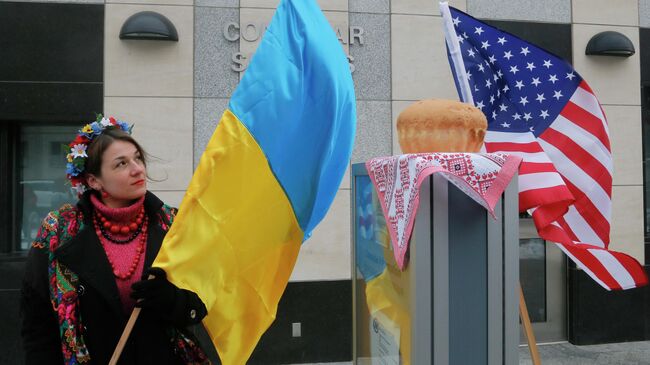 Женщина держит флаг Украины рядом с посольством США в Киеве