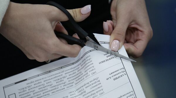 Члены избирательной комиссии проводят процедуру гашения неиспользованных бюллетеней на избирательном участке
