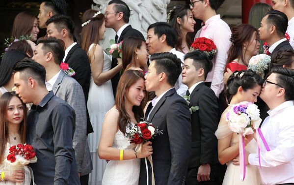 Молодожены целуются во время массовой свадебной церемонии в Куала-Лумпуре, Малайзия