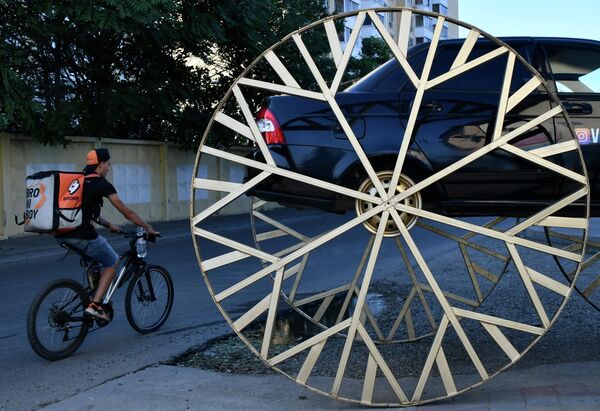 Автомобиль LADA Priora с установленными двухметровыми колесами, стилизованными под колеса кареты, на одной из улиц Краснодара
