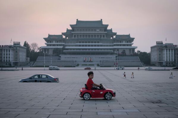 Мальчик на электрическом игрушечном автомобиле на площади имени Ким Ир Сена в Пхеньяне