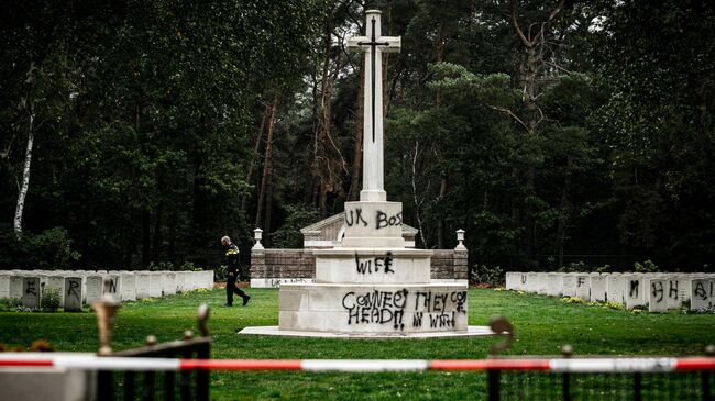 Сотрудник полиции на оскверненном вандалами мемориале в память о жертвах Второй мировой войны в городе Миерло, Нидерланды. 13 сентября 2019