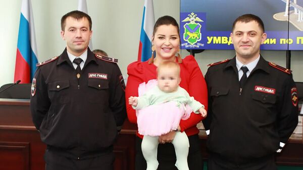 Сотрудники полиции Евгений Мельничук и Ариф Мурадханов со спасенной девочкой и ее мамой