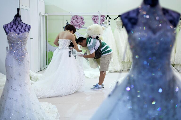 Мужчина помогает своей девушке выбрать свадебное платье в Пекине 