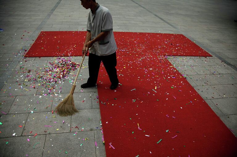 Рабочий убирает конфетти после свадебной церемонии в Пекине, Китай 
