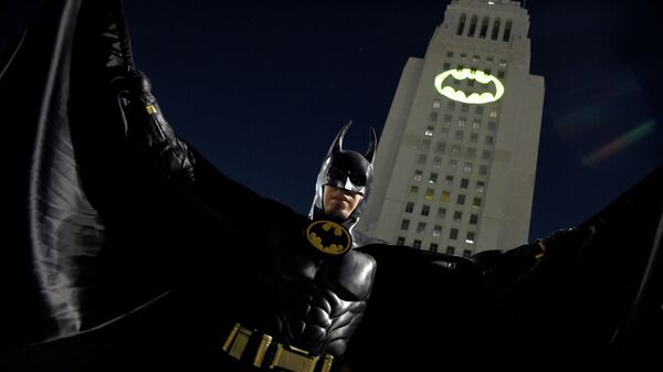 Мужчина позирует перед Bat-Signal, проецируемым на здание муниципалитета в Лос-Анджелесе