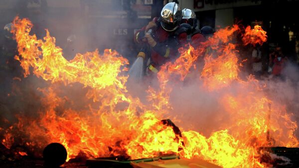 Пожарные тушат баррикаду во время акции протеста, призывающей власти принять экстренные меры против изменения климата, в Париже. 21 сентября 2019