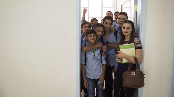 Школьники с учительницей в классе открывшейся в районе Барза в Дамаске школы, отремонтированной на собранные в России средства