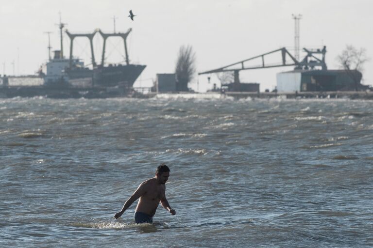 Мужчина купается в Азовском море в Мариуполе