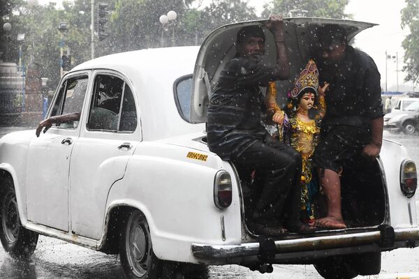 Индуистские преданные перевозят статую Вишвакармана для церемонии погружения в Калькутте
