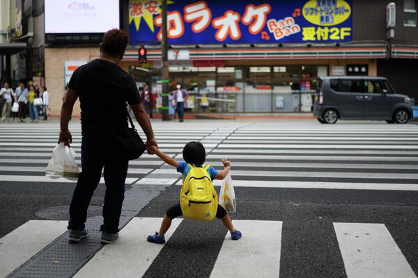 Мужчина c ребенком на пешеходном переходе в центре Оиты, Япония
