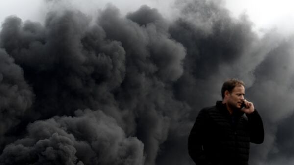  Мужчина на дороге в Ле-Пети-Кевилли в дыму от пожара на фабрике Lubrizol. 26 сентября 2019 
