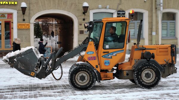 Сотрудник коммунальной службы с помощью спецтехники убирает снег в центре Санкт-Петербурга