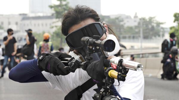 Участник протестов в Гонконге наводит в сторону полиции лазерную указку