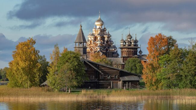 Преображенская церковь XVIII века после реставрации, церковь Покрова Пресвятой Богородицы и колокольня, входящие в состав архитектурного ансамбля Государственного историко-архитектурного музея-заповедника Кижи, на острове Кижи Онежского озера в Карелии