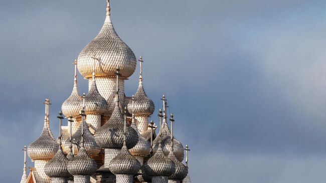 Купола, покрытые новыми осиновыми лемехами, Преображенской церкви XVIII века, входящей в состав архитектурного ансамбля Государственного историко-архитектурного музея-заповедника Кижи, на острове Кижи Онежского озера в Карелии