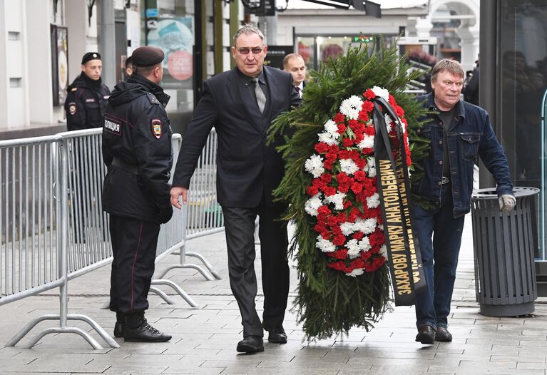 Мужчины с венком у здания театра Ленком в Москве, где проходит церемония прощания с режиссером Марком Захаровым