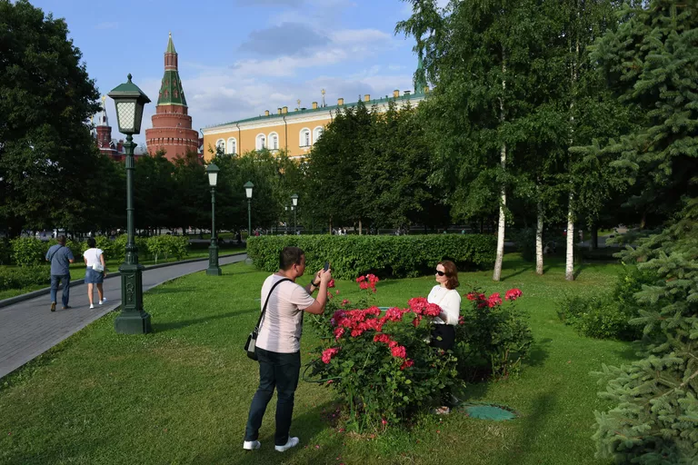 Молодой человек фотографирует девушку в Александровском саду в Москве Молодой человек фотографирует девушку в Александровском саду в Москве