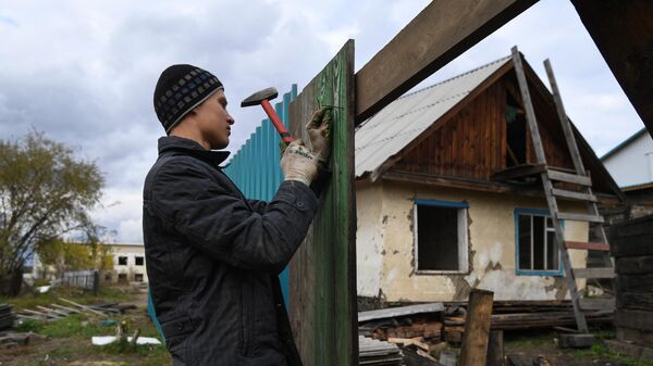 Мужчина ремонтирует забор, поврежденный наводнением в Тулуне