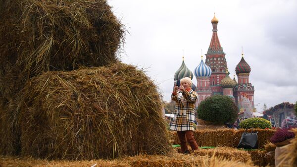 Посетительница фестиваля Золотая осень фотографирует стог сена на Красной площади