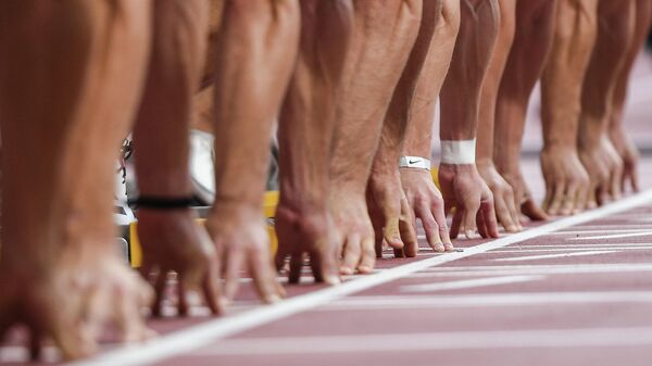 Руки спортсменов на старте забега 100 м в соревнованиях по десятиборью на чемпионате мира по легкой атлетике 2019 в Дохе.