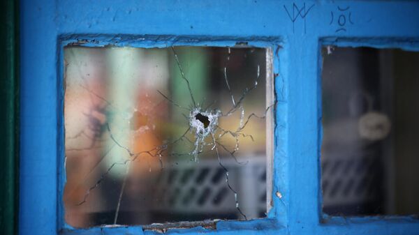 Окно жилого дома, разбитое осколком снаряда, в поселке Старомихайловка Донецкой области