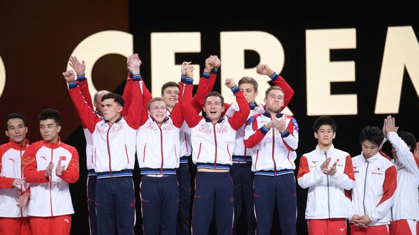 Спортсмены сборной России (в центре), завоевавшие золотые медали в командном многоборье среди мужчин, на церемонии награждения на чемпионате мира по спортивной гимнастике в Штутгарте.