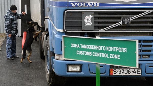 Сотрудник таможенной службы РФ с собакой осуществляет досмотр автомобиля на контрольно-пропускном пункте Бугристое российско-казахстанской границы