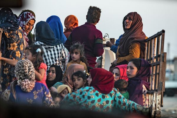 Жители уезжают из-за турецкой бомбардировки северо-восточного города Сирии Рас-эль-Айн в провинции Хасаке вдоль границы с Турцией
