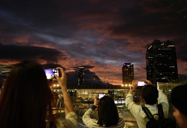 Люди фотографируют закат в Осаке, Япония. 12 октября 2019