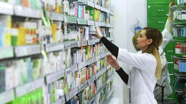 Фармацевт раскладывает лекарственные препараты в аптеке. Архивное фото