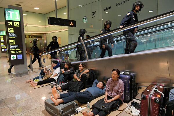 Испанские полицейские проходят мимо пассажиров, ожидающих в аэропорту Эль-Прат в Барселоне